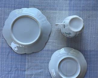 Bottom side of small white, floral saucer and cup with gold details 