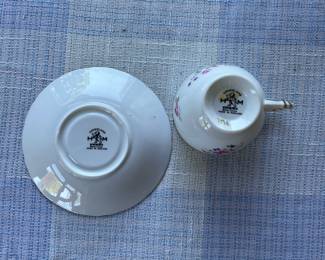 Bottom side of small white, floral saucer and cup with gold details