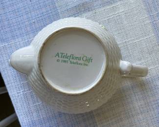 Bottom side of textured white ceramic teapot with pink and green floral design 