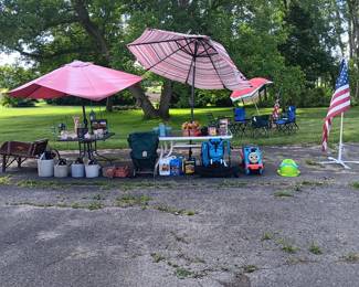 Antique flower cart, umbrellas, crocks, jugs, deck cleaner, golf balls, 2 hiking backpacks, ridable engine, American flags, 2 patio chairs with cushions, 4 camping chairs, various garden decorations.