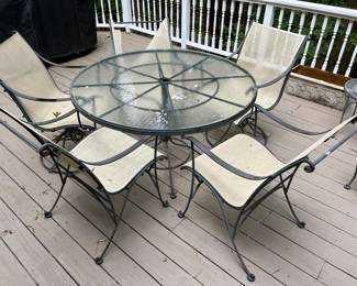 Glass-top metal patio table with five chairs (two chairs with fabric in need of repair).