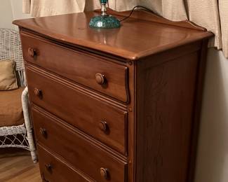 In one of the other rooms is this four-drawer dresser and lamp.