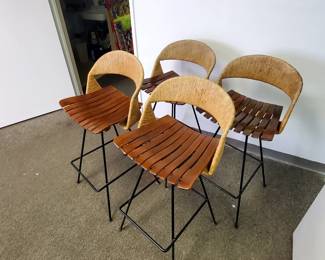 We are selling these four Arthur Umanov designed Stools as a set of four.  These vintage mid-modern stool swivel, have slatted wood seats, wicker backs. and solid black steel construction.  The seat height of the stools is 29 1/2 inches tall.  