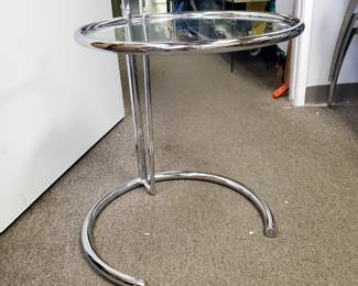 We are selling this beautiful and modern polished steel and glass end table. This adjustable table measures 20 1/8" wide and 21" tall.