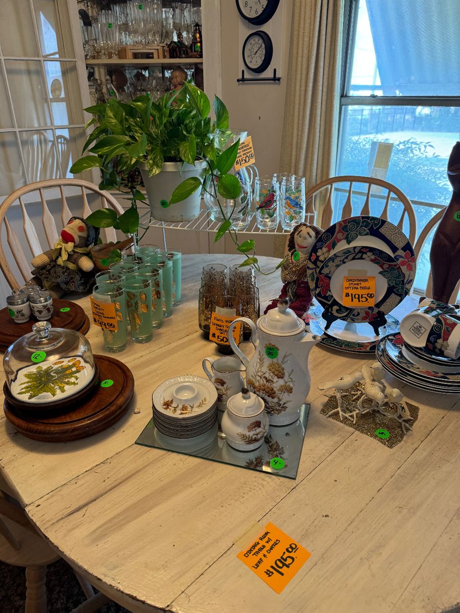 Dining room table, full of vintage dishware, glass sets, and collectibles.
