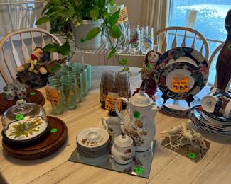 Dining room table, full of vintage dishware, glass sets, and collectibles.