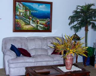 Plush upholstered couch, intricate wooden glass top coffee table, beautiful painting artwork