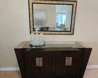 Fabulous contemporary console cabinet with gold trim and glass top. Matching beveled mirror with gold trim