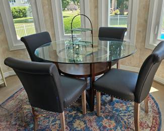 48" Round glass top table with wooden base. Four parson chairs with nail head trim.