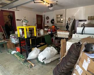 Garage is packed full of items including herb drying racks, canning supplies, tools, decor, holiday items, and even a washer and dryer.