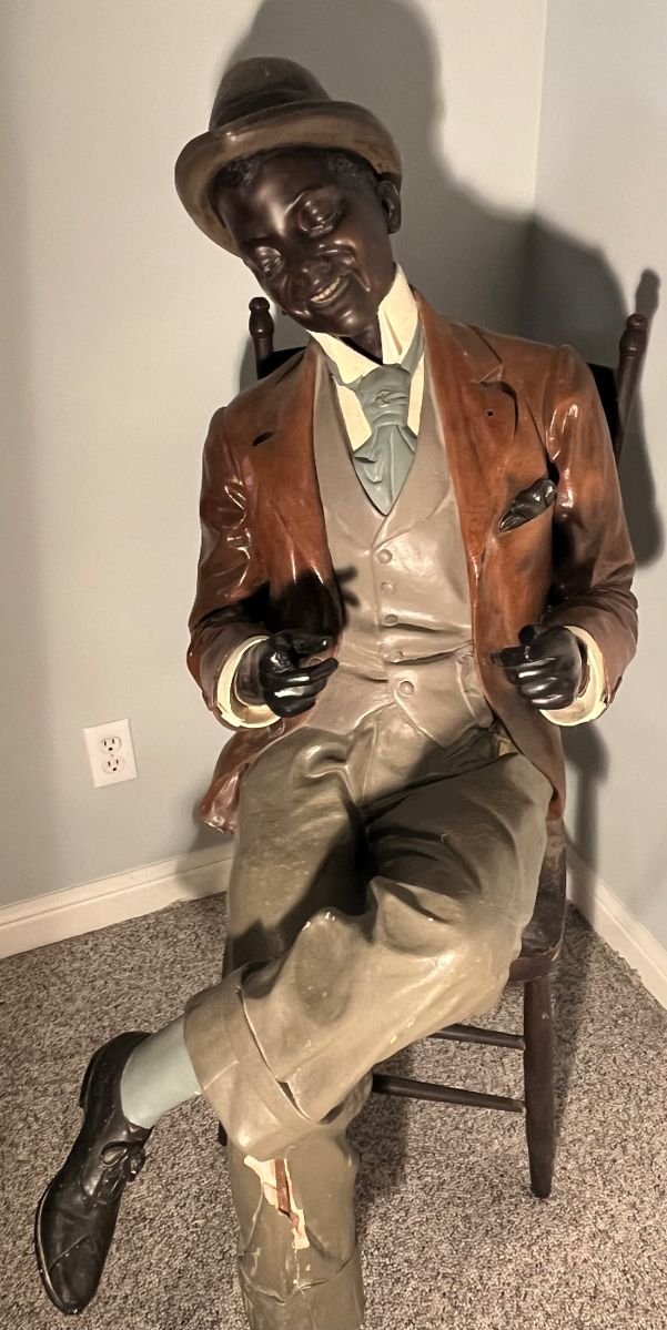 Lower Level:  A life-size polychrome man has been in the family for many years.  He was living in an old warehouse on Franklin Avenue in 1936 when our client's family purchased the building for their barber supply business.  He became a prominent spokesperson for the family business, and they named him "Waldo."  In the 1950's, a startled police officer walking the warehouse beat accidentally shot his fingers off.   Waldo moved with the family throughout the years, losing his left foot at one time.  Eventually, he was moved from the barber chair to the family dining chair where he still sits today.  He has been a part of the family for over 90 years but does not wish to make the move to Kansas City--he prefers to stay in in St. Louis.  He will be homeless soon.   The next photo shows a close-up of his face.  