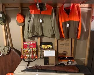 Lower Level:  Hunting caps and jackets are near target practice items, clay pigeons, and two empty gun cases. 