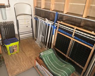 Lower Level:  A heater on casters and a box of cat litter are to the left of one hard plastic folding chair.  Also shown are two safety gates and a putting green (see next photo).