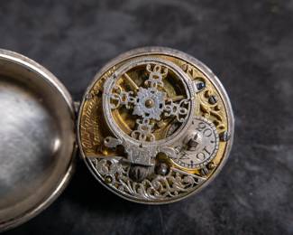A silver pocket watch held in a silver case, made by Will Kipling of London. Circa 1720's. A silver face with Roman and Arabic numerals and a date counter. Engraving "K0266". Inside is marked "TN" and "1065". 1065 is also marked on the watch mechanism and is believed to be the pieces serial number. No key.
