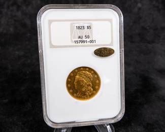 An 1823 $5 Capped Bust Half-Eagle Gold Coin. Graded an AU-50 by NGC. This coin also has a CAC Gold Sticker, meaning CAC believes the quality of the coin may warrant a higher grade. It is estimated there are 80 to 100 surviving examples of this coin. The design features are well brought up in most areas. The semi-reflective green-gold surfaces display pleasing coral color near the peripheries.