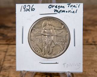 A 1926 50C Oregon Trail commemorative half-dollar. Estimated AU condition.