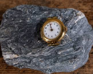 An 18k gold lady's wrist watch. The watch is missing it's glass cover but is still ticking and working. Serial #636653. Total weight 13.84 grams.