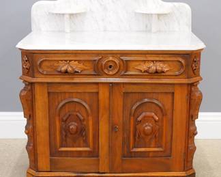 A 19th century Victorian Renaissance Revival period bedside commode. Walnut construction with White marble top features a shaped backsplash with two candle shelves on a base with one long drawer and carved fruit pulls over two paneled doors and a molded base. Refinished with minor wear. 35 x 19 x 41 1/2" high overall. NOTE: This lot picks up from our Ypsilanti, Michigan facility.