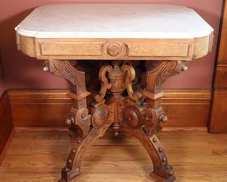 A 19th century Victorian Period parlor table. Walnut construction with Burl detail, shaped Marble top and conforming apron over a carved stretcher base with turned stem and curved legs. Older dull finish with minor wear, some shrinkage, a few small repairs, minor losses to Burl inlay, lacks a piece of molding. 31 x 22 1/2 x 29 1/2" high overall. NOTE: This lot picks up from the home in Coldwater, Michigan.