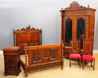 A late 19th century Victorian Period five piece bedroom set. Oak construction with extensive hand carved decoration depicting 19th century rural life, features a wardrobe with shaped crest above a geometric frieze and two long doors with shaped beveled mirrors flanked by spiral turned columns over a single long drawer and turned bun feet (57 x 25 1/2 x 102" high disassembles for moving) a large bed with shaped crest, turned finials, spiral turned posts and raised panel detail carved geometric side rails and a footboard with figural panels and spiral turned posts (58 x 75 x 63" high) a bedside stand with inset marble top over a single drawer and paneled door (19 x 15 x 35" high) and two chairs with spiral turnings, shaped crests, upholstered seats and stretcher bases (each 16 1/2 x 16 x 42 1/2" high). Older finish with minor wear, some flaking to mirror silvering, bed lacks several small moldings, minor shrinkage. NOTE: This lot picks up from our Ypsilanti, Michigan facility.