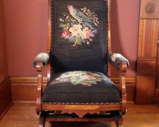 A 19th century Victorian Period rocking chair. Walnut construction with Burled detail, carved crest over a needlepoint upholstered back, arms and seat on a platform rocking base. Older refinishing with minor wear and scuffs, some shrinkage, upholstery with some pulls, fading and minor losses. 24 x 28 x 42 1/2" high overall. NOTE: This lot picks up from the home in Coldwater, Michigan.