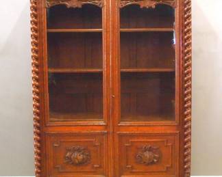A late 19th century Victorian Period bookcase. Oak construction with extensive hand carved decoration features a molded cornice above a carved foliate frieze and two long doors with original glass panes and carved lower panels flanked by spiral turned columns on a base with one long drawer and carved Owl mask pull on turned bun feet. Old finish with minor wear, adjustable interior shelves, completely disassembles for moving. 58 x 20 x 90 1/2" high overall. NOTE: This lot picks up from our Ypsilanti, Michigan facility.