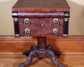 An early 19th century Empire Period work table. Figured Mahogany construction features a top drawer with folding felt work surface over two drawers flanked by lacquered pilaster on a pedestal base with carved paw feet. Older finish with wear, shrinkage and minor damage, cracks to veneer at base, replaced drawer pulls. 22 1/4 x 18 x 29 1/2" high overall. ESTIMATE $200-400 NOTE: This lot picks up from the home in Coldwater, Michigan.
