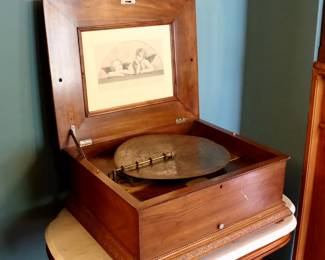 A late 19th century Victorian Period Symphonion music box and thirteen disc. Single comb crank wind movement, plays 14 3/4" discs. Mahogany case with molded lift top and base. Scrapes to the top and front, minor damage and losses to molding, running and playing when cataloged. 23 1/2 x 20 1/2 x 11" high overall. ESTIMATE $300-500 NOTE: This lot picks up from the home in Coldwater, Michigan.