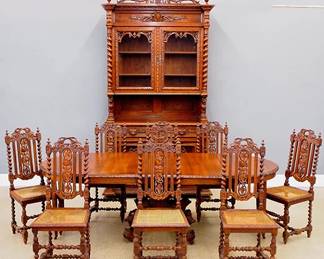 A late 19th century 10 piece Victorian Period dining room set. Oak construction with extensive hand carved decoration features a stepback hunt cupboard with Deer and foliate crest over two glass doors and an open serving area with carved Lion supports on a base with two silverware drawers and two lower doors with carved game panels (55 x 24 1/2 x 109 3/4" high), a round extension table with turned central pedestal and animal figures on the scrolled legs (45" diameter x 30" high plus three matching 16 1/4" extension leaves) and eight carved chairs with caned seats (each 18 x 16 x 43" high). Restored finish with minor wear, minor damage to the seats, leaves are custom made replacements. ESTIMATE $2,000-4,000 NOTE: This lot picks up from our Ypsilanti, Michigan facility.