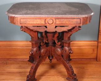 A 19th century Victorian Period parlor table. Walnut construction with Burl detail, shaped Marble top and conforming apron over a carved stretcher base with turned stem, curved legs. Older finish with some wear, shrinkage and minor damage, some losses to Burl inlay, Marble with some discoloration, ring marks and scratches. 32 x 23 x 29 1/2" high overall. NOTE: This lot picks up from the home in Coldwater, Michigan.