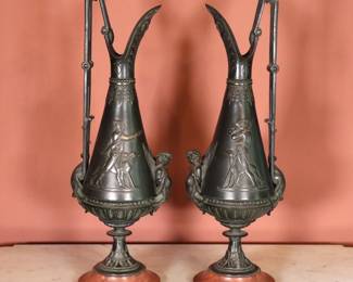 A pair 19th century Neoclassical Bronze ewers. Tapered form with cast design depicting a Huntsman and Cherub on shaped Marble bases. Stamped letters at undersides. Minor oxidation and slight pitting, minor flakes to Marble edge, both lack finials at handle. Each 4 1/2 x 4 1/2 x 16 1/2" high overall. NOTE: This lot picks up from the home in Coldwater, Michigan.