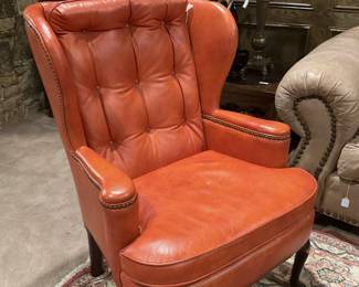 Orange leather wingback chair with nailhead trim