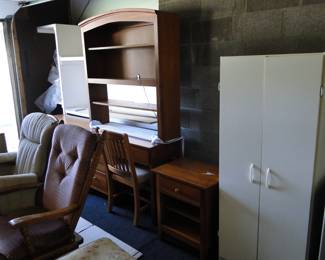 Moving from right to left, tall white storage cabinet, nightstand, desk, with hutch