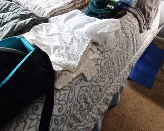 Bed loaded with hats, bed ruffles and blankets +