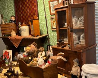 ANTIQUE CHILDS CHINA CABINET WITH DISHES AND ANTIQUE CRADLE FULL OF STEIFF STUFFED ANIMALS