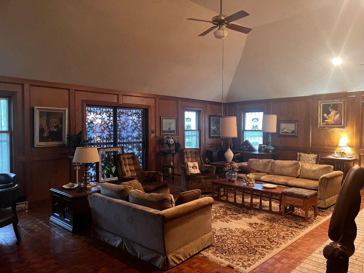 Gold velvet entertaining/conversation couches, matching gold swivel chairs, large vintage area rug, brass lamps, collectible lamps, large framed artwork, wooden sculptures.