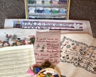 many cross stitch pieces, patterns, thread, unfinished pieces, supplies