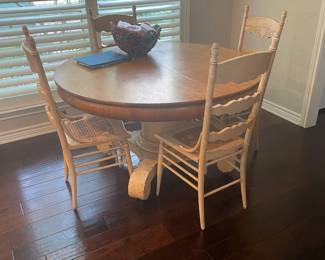 Blonde pedestal table with four cane-seated straight back chairs