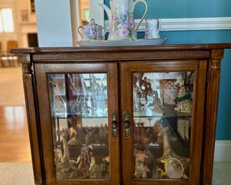 Broyhill illuminated cabinet holds a collection of giraffe figurines.
