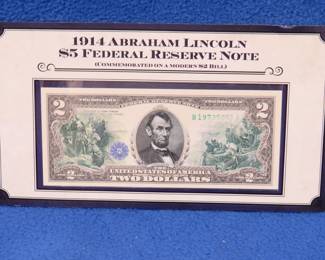 Lot 310. 1914 Abraham Lincoln $5 Federal Reserve note overlayed on a modern $2 bill