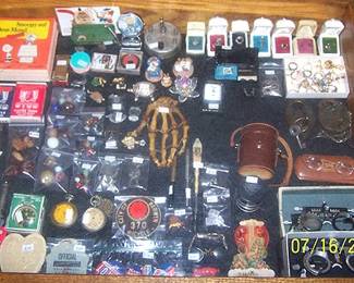 Display case of smalls including human hand, Sterling rings, Peanuts books written in German, pocket watches,  P. Angenieux camera lens, antique bicycle license and more.