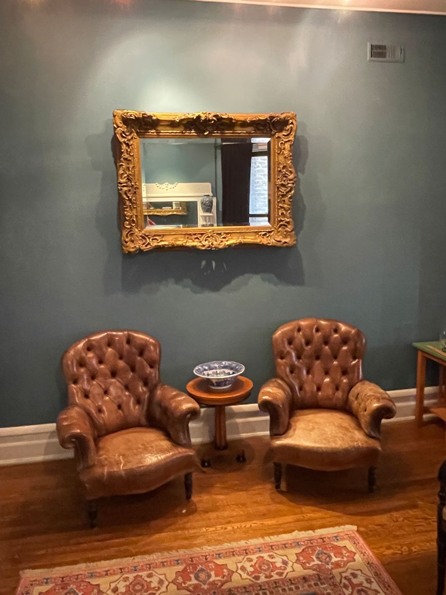 Pair of Ralph Lauren Home button tufted leather chairs (one seat with tear), Massive Antique English Carved and Gilded Beveled Mirror and Biedermeier style side table with birds-eye maple top