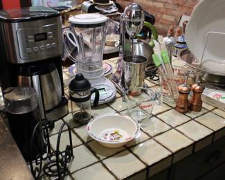 Assorted cookware including Cuisinart drip coffeemaker, coffee grinder, mini French press, two Pyrex liquid measuring cups, rose gold salt and pepper shaker, an Oster blender, and a stainless steel shake maker