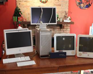 Several vintage Apple computers including two iMac 2006, two white mac keyboards, a Power Mac tower, an Apple Cinema Display monitor, and two Apple eMac all-in-one desktop computers