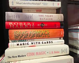 Even more books including "What Color is Your Parachute: Job Hunters Manual 1990", "The Night Manager" by John Le Carré, "Enigma" by Robert Harris, Isaac Asimov's Book of Facts, "Las Vegas Access", "Magic with Cards", "The New Modern Coin Magic" by JB Bobo, "A World of Ideas" by Bill Moyers, New York Times Sunday Crossword Puzzles Volume 28