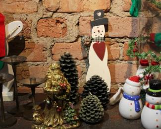 Assorted tabletop Christmas decor including three pine cone candles and some snowmen
