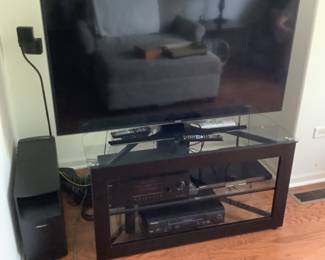 Flatscreen smart tv and stand plus components. Components are: Bose speaker ( on left) with two front and two back speakers on stands. A Sony piece and Panasonic piece.