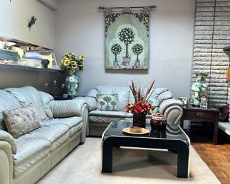 Taupe leather couches, 2 side tables, vases, pictures, coffee table