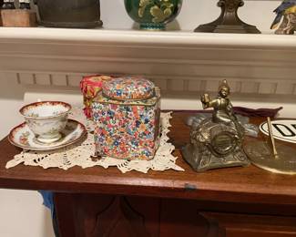 Teacup, vintage floral tin container, and vintage cast iron man.