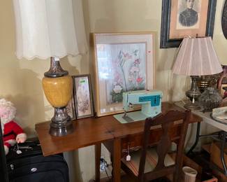The Singer sewing machine and sewing cabinet is shown here, as well as a couple of lamps and more framed artwork pieces.